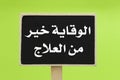 Prevention Is Better Than Cure written in Arabic on a chalkboard against green background